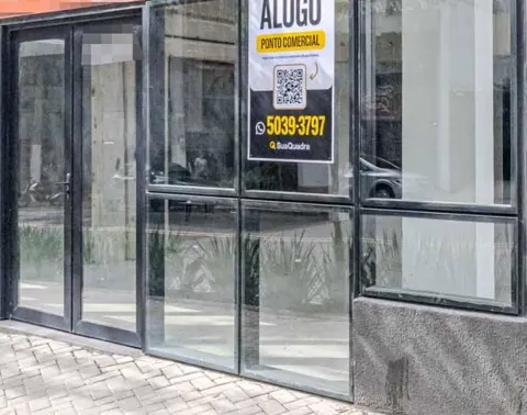 Placa ALUGO ponto comercial da SuaQuadra na vitrine de uma loja de rua